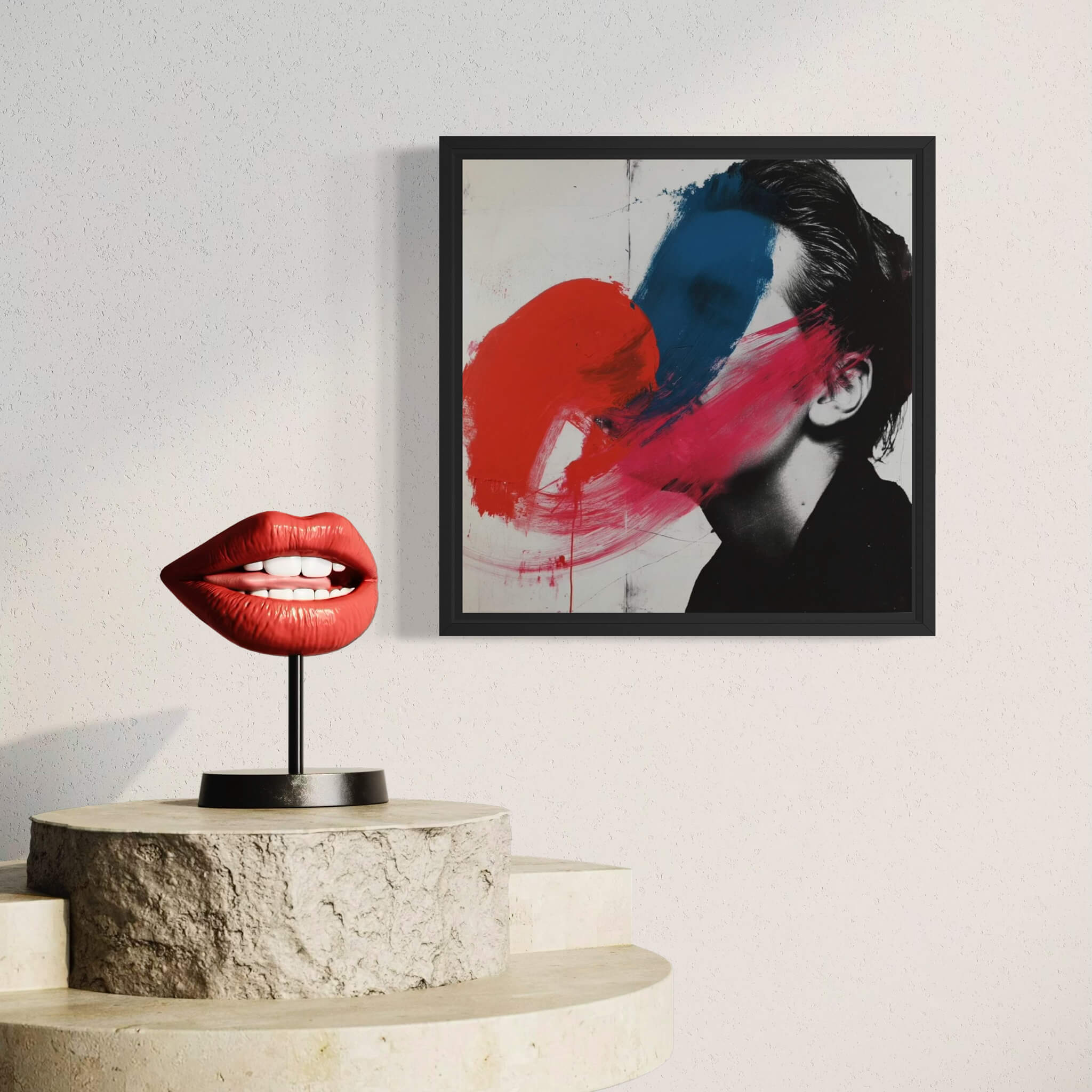 Framed abstract art with red and blue colors on a wall above a sculpture of red lips.