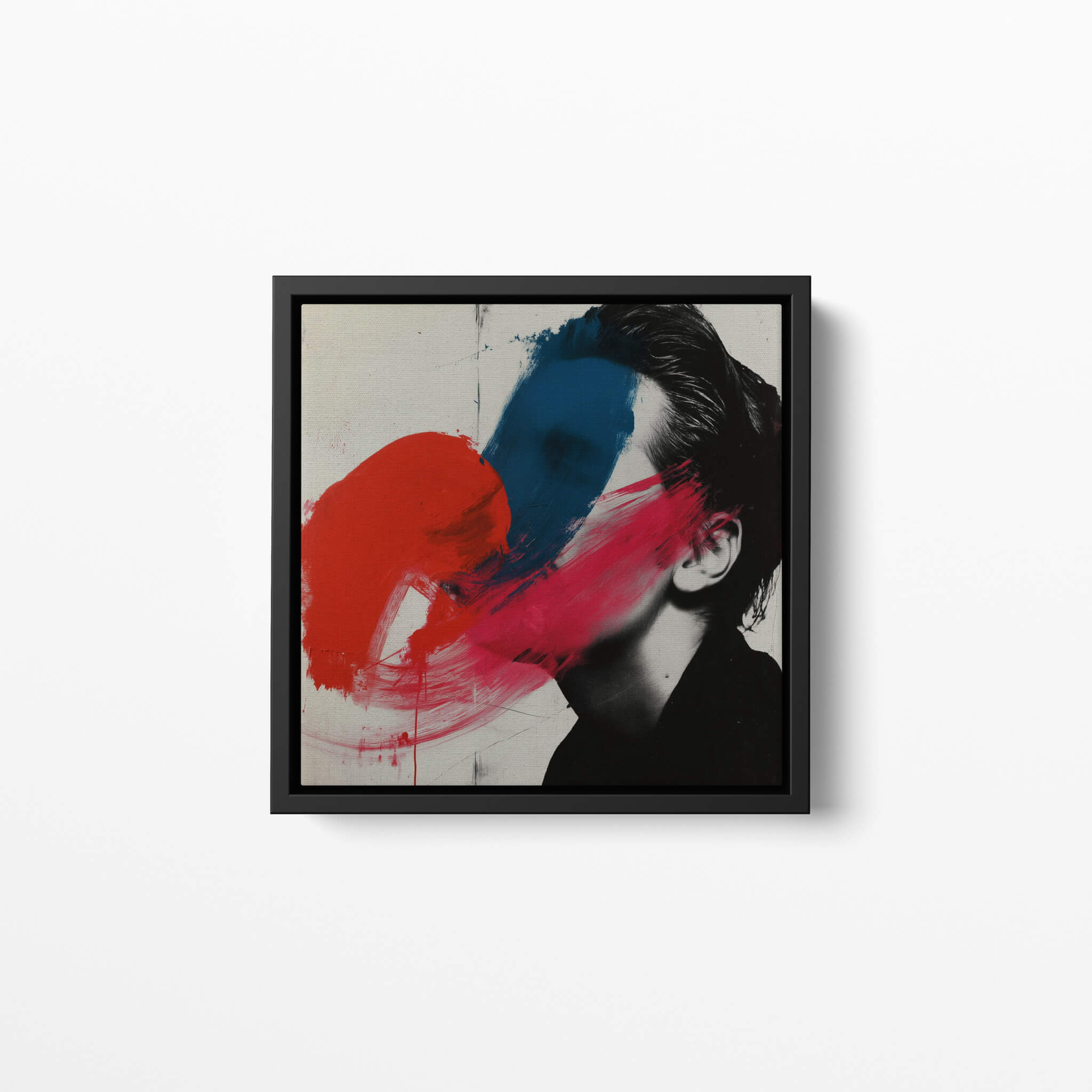 Framed abstract art piece with red and blue brushstrokes on portrait photography, on a white wall.