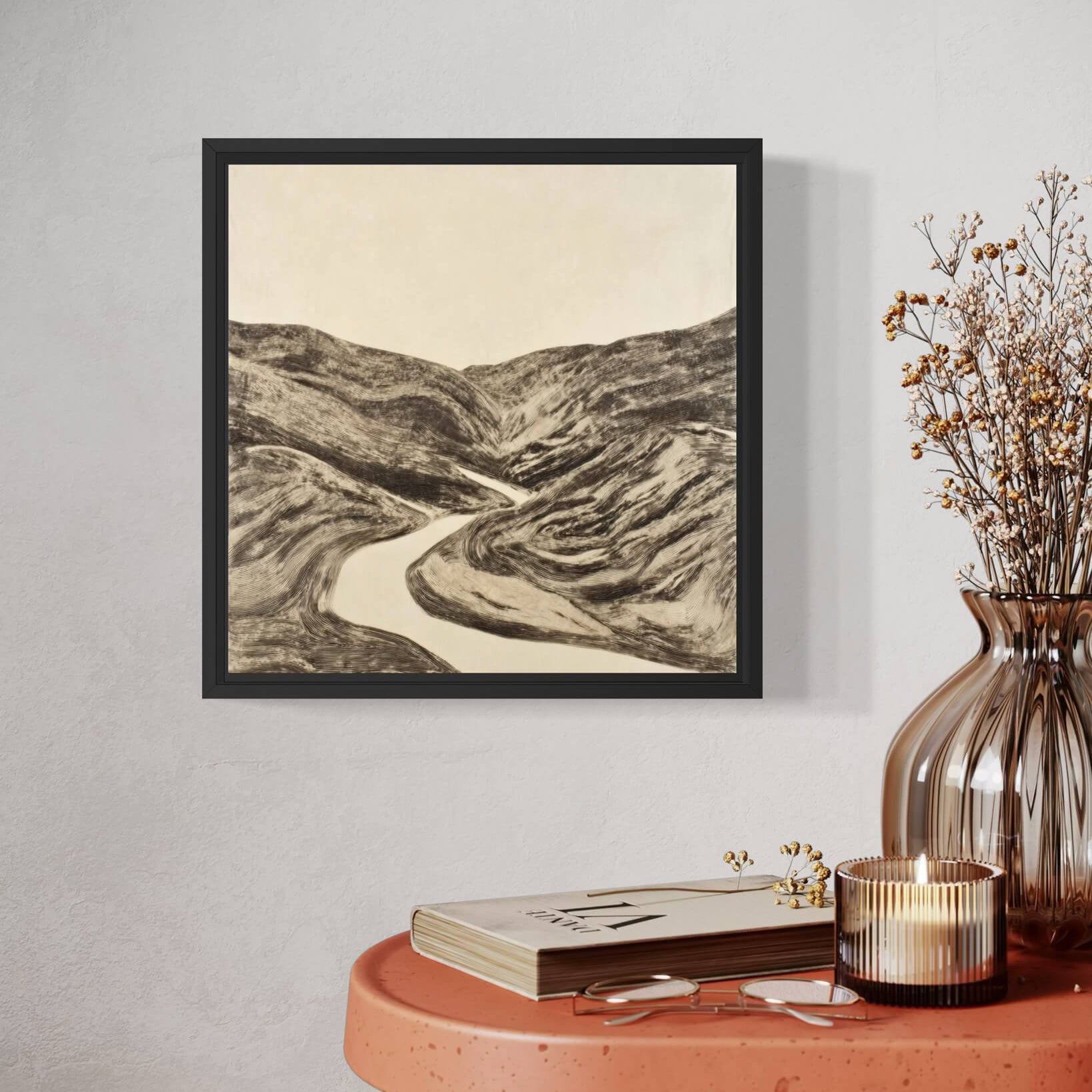 Framed landscape fine art print on a wall above a table with decor items.