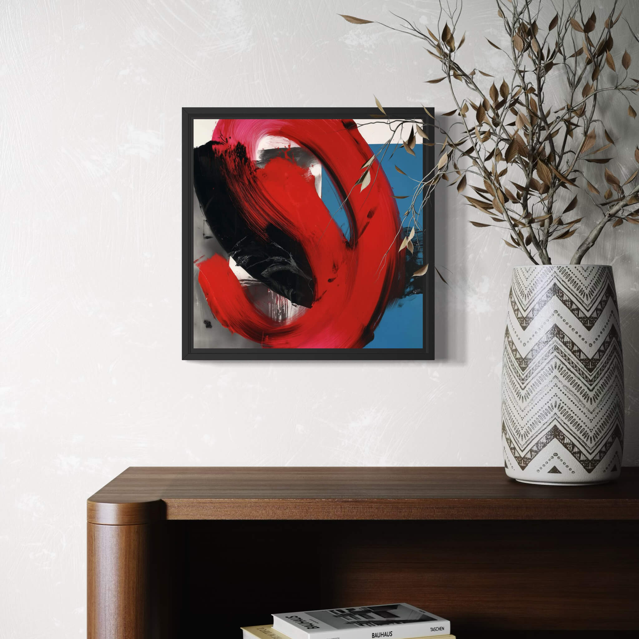 Abstract painting with red and black abstract design on a wall above a wooden shelf with a vase and books.