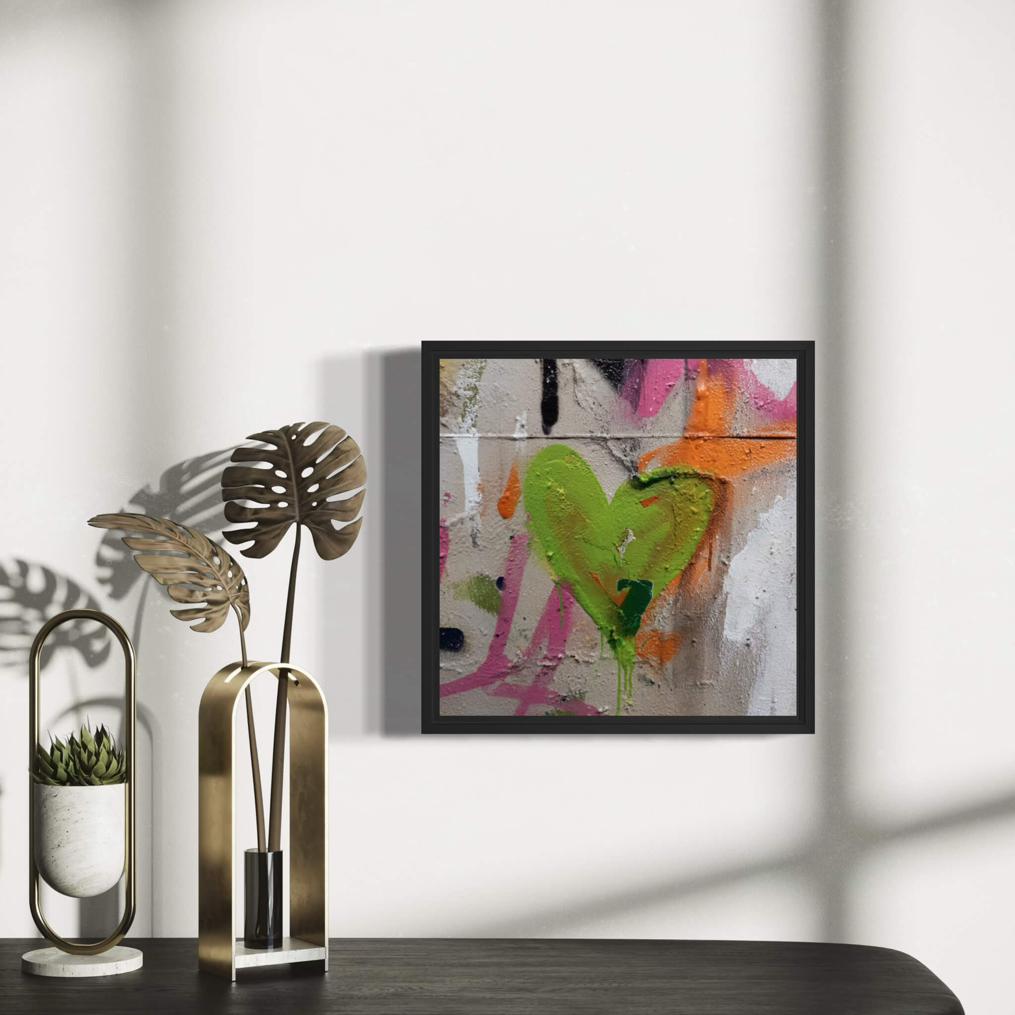 Framed abstract painting with a graffiti heart design on a wall above a table with decorative items.