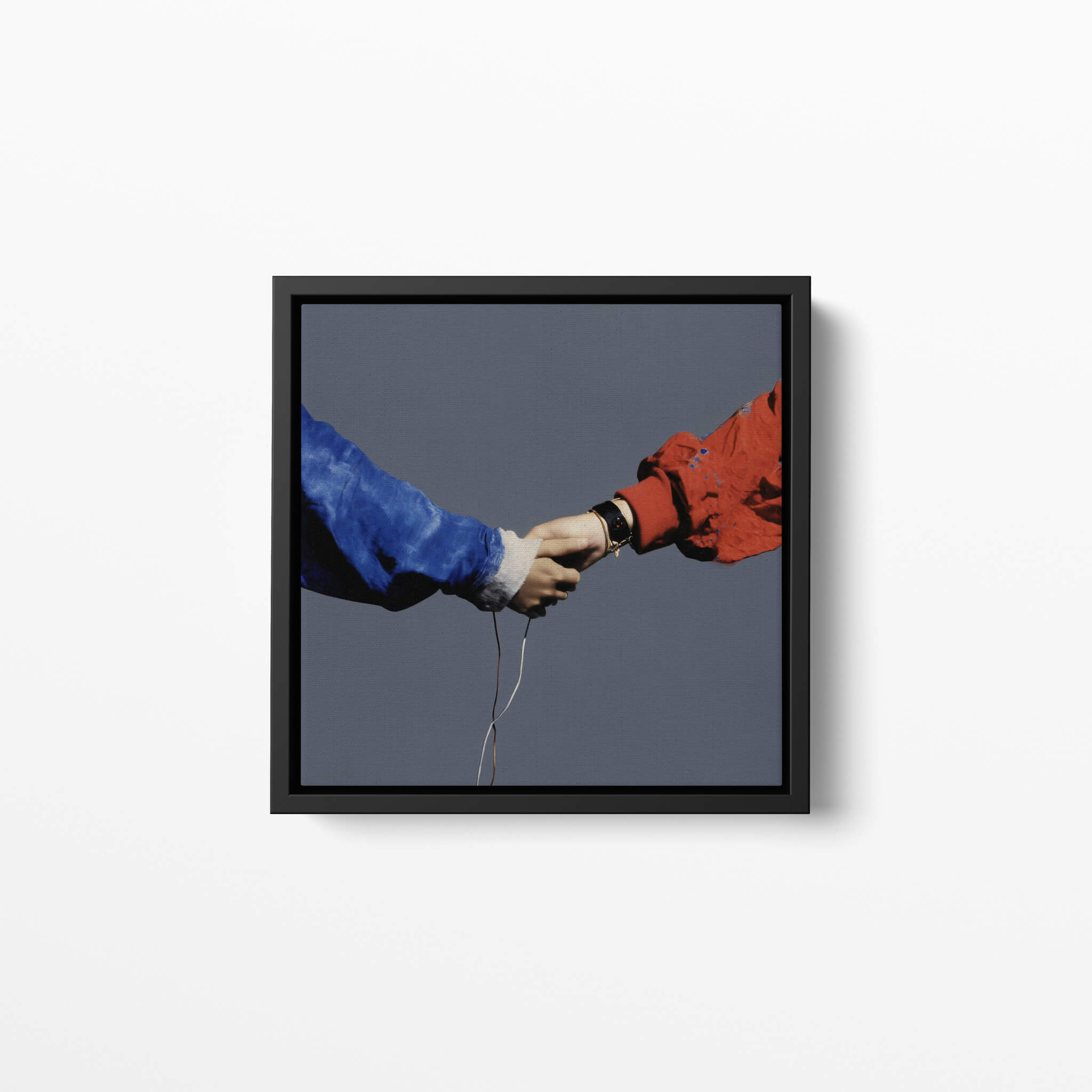 Framed artwork of two hands reaching towards each other with a gray background