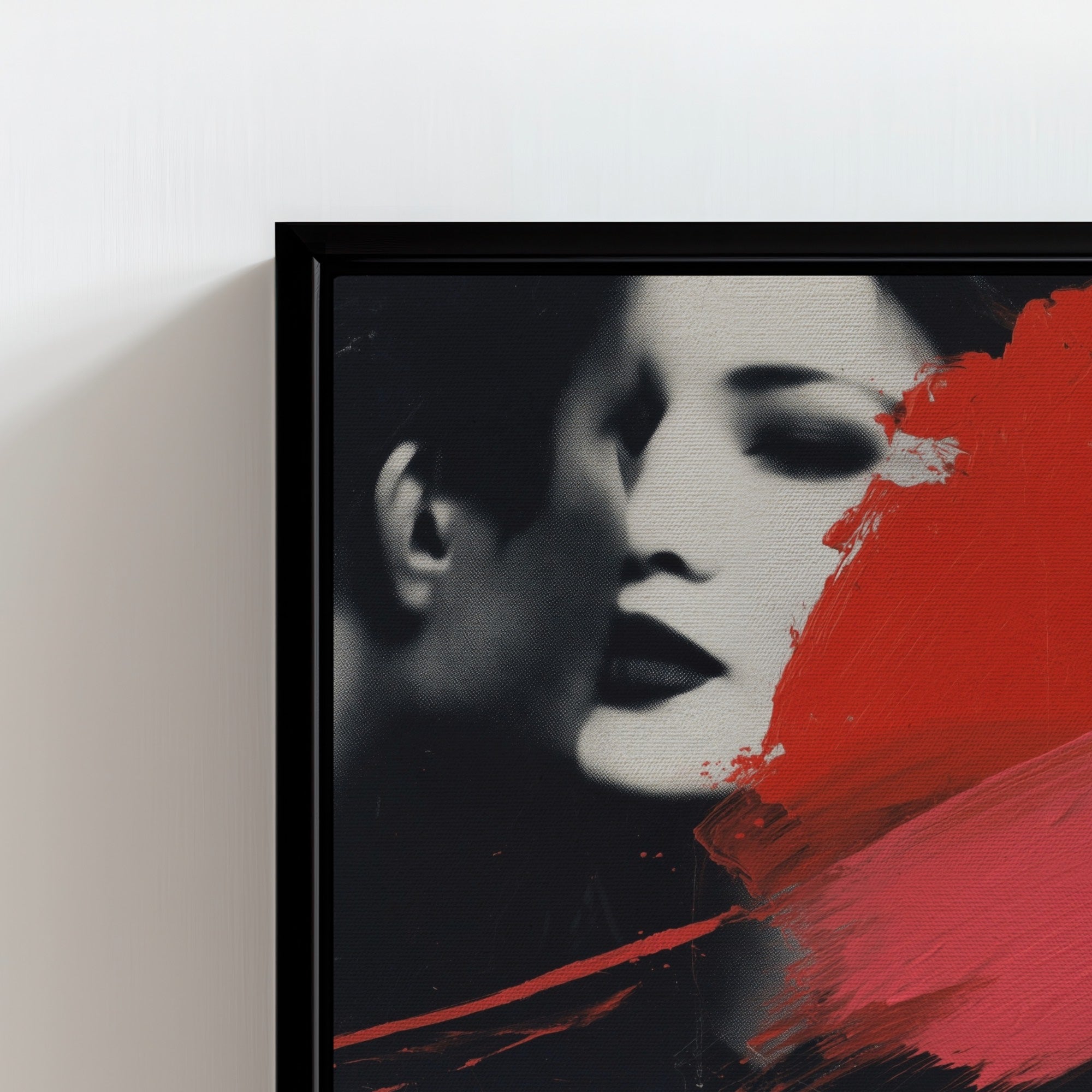 Framed artwork of a stylized portrait with red and black abstract elements on a white wall.